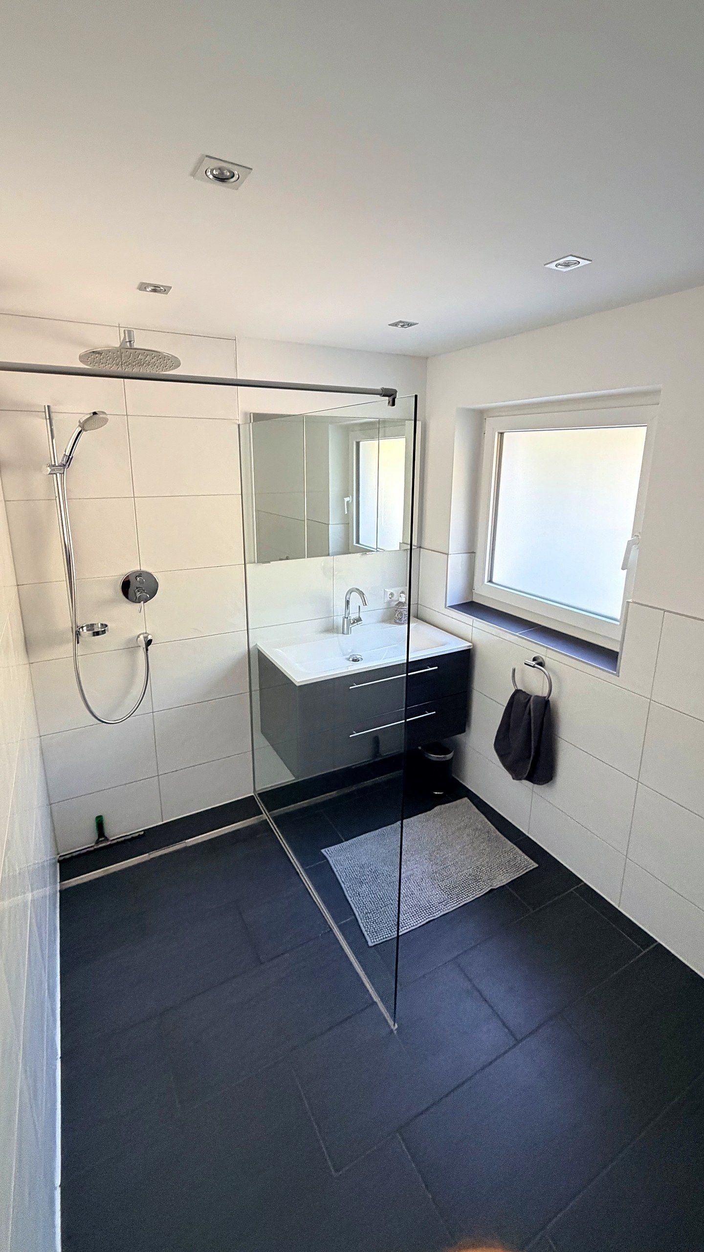 Bathroom with walk-in glass shower, rain shower and vanity unit