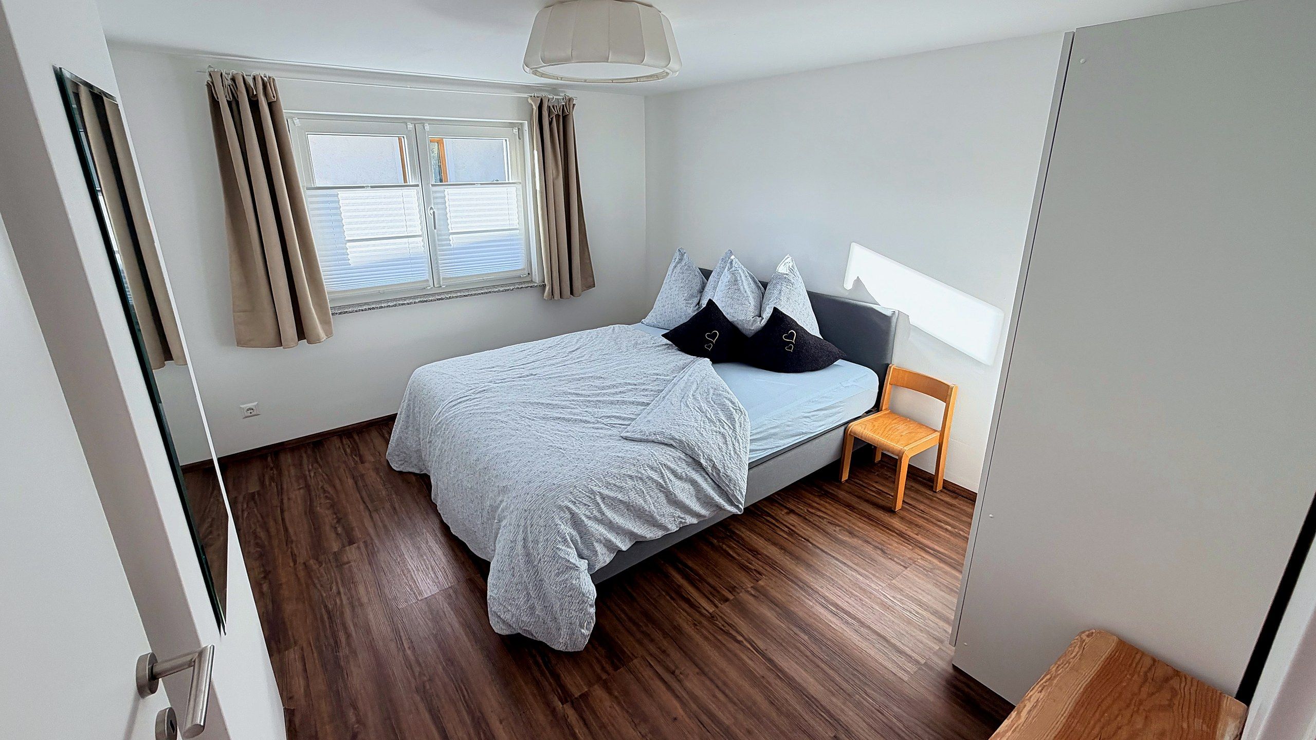 Second bedroom with double bed, light grey bedding and a wooden chair